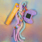 Full view of the chunky keychain featuring a lilac mini gaming controller and a multicolored Fuzzy Keychain tassel in pastel pink, purple, and mint
