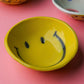 Yellow ceramic smile bowl featuring hand-painted happy face design