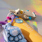 unicorn figurine key charm with yellow dali balm and blue patterned ribbon