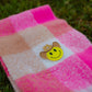 Close-up of smiley western pin on bright pink and sand checkered kids scarf