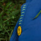 Close-up of yellow smiley badge and neon hand stitch detail on denim blue joggers